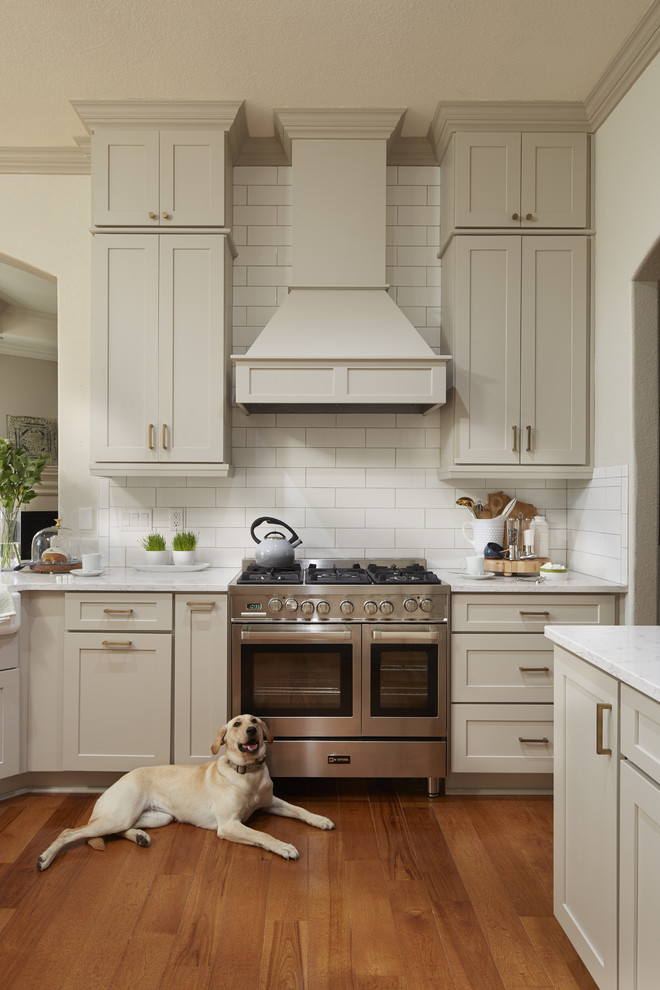 Enclosed kitchen - mid-sized transitional u-shaped medium tone wood floor and brown floor enclosed kitchen idea in Atlanta with a farmhouse sink, shaker cabinets, gray cabinets, quartz countertops, white backsplash, subway tile backsplash, stainless steel appliances, a peninsula and white countertops