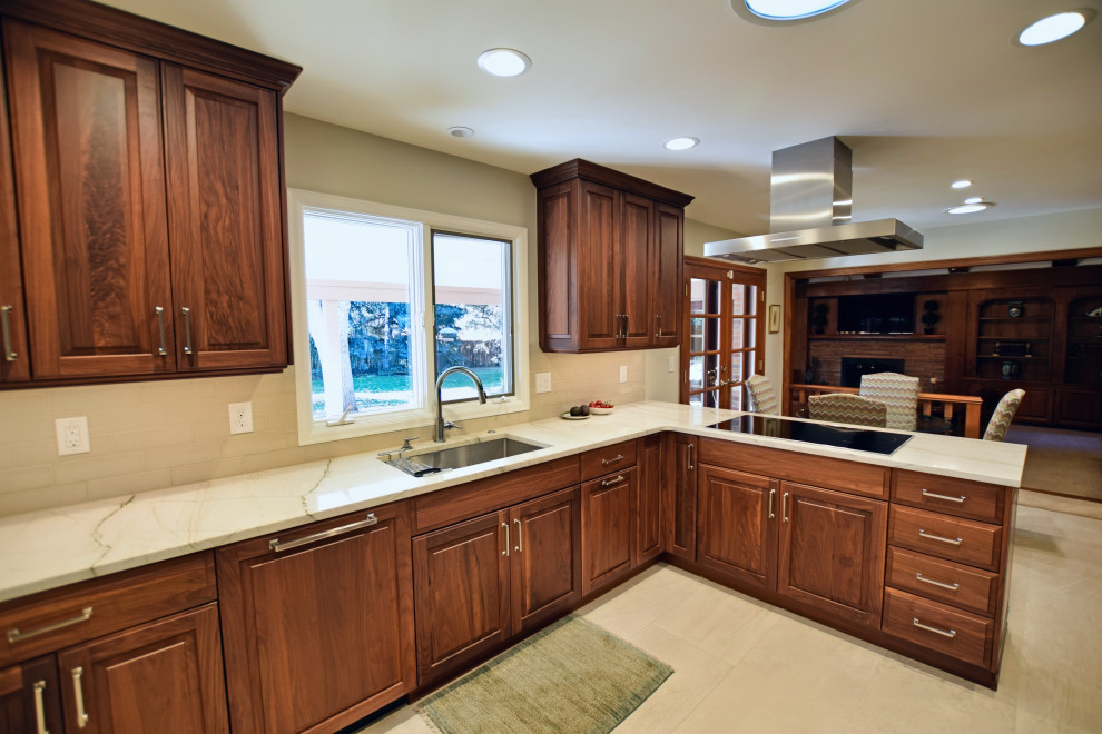 This is an example of a large traditional u-shaped kitchen/diner in Denver with a submerged sink, raised-panel cabinets, dark wood cabinets, stainless steel appliances and white worktops.