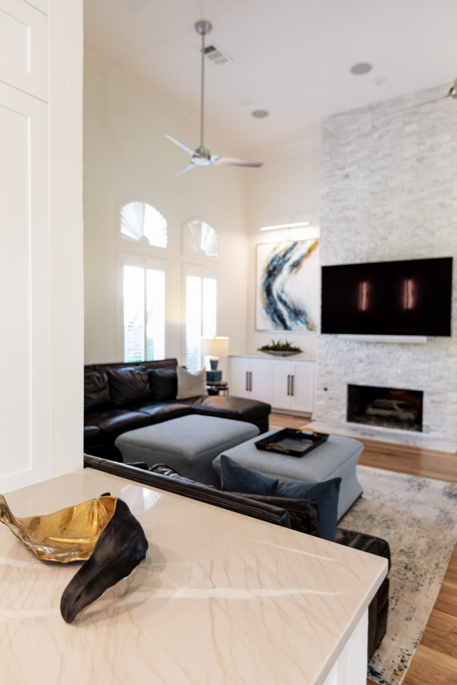 Großes, Offenes Modernes Wohnzimmer mit weißer Wandfarbe, hellem Holzboden, Kamin, Kaminumrandung aus gestapelten Steinen, TV-Wand und braunem Boden in Dallas