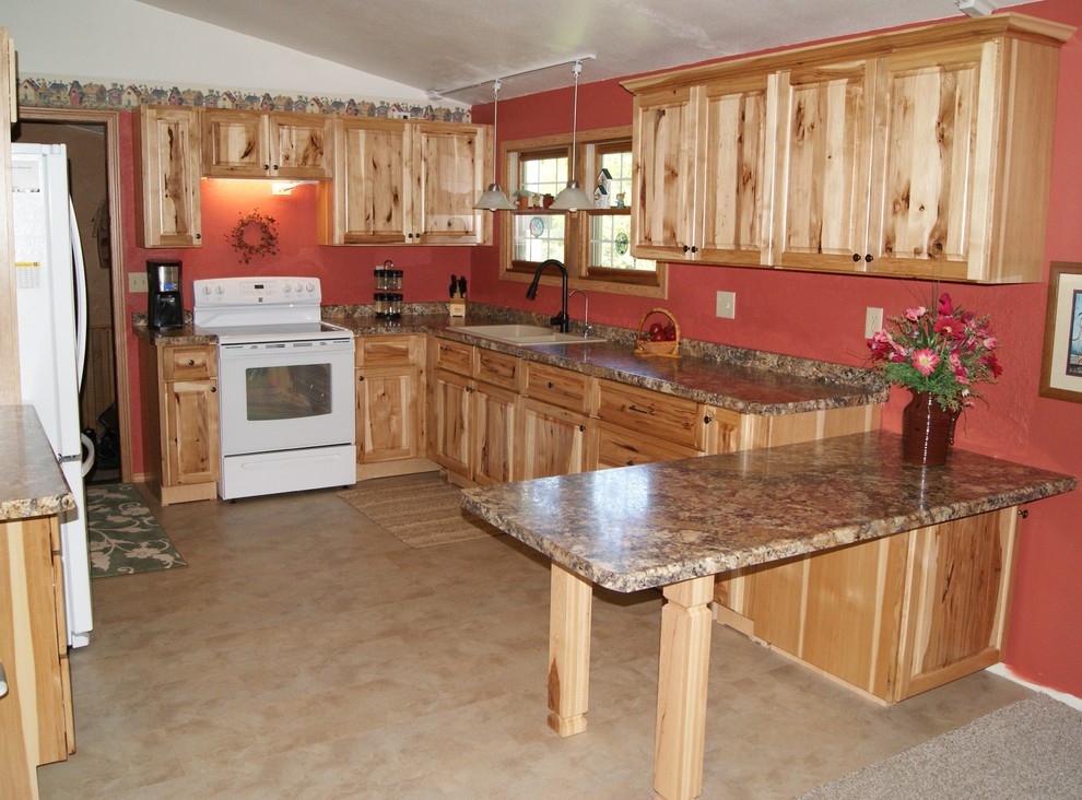 Example of a mid-sized mountain style u-shaped travertine floor enclosed kitchen design with a drop-in sink, raised-panel cabinets, light wood cabinets, granite countertops, white appliances and a peninsula
