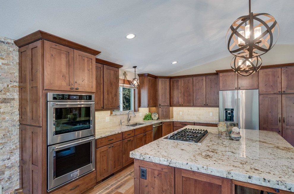 Large mountain style l-shaped medium tone wood floor and brown floor enclosed kitchen photo in Denver with an undermount sink, shaker cabinets, medium tone wood cabinets, granite countertops, beige backsplash, stone tile backsplash, stainless steel appliances and an island