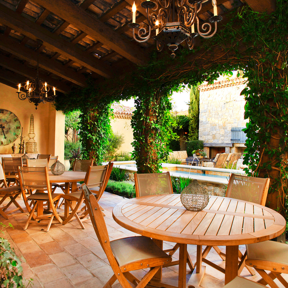Inspiration for a country courtyard patio in Orange County with a water feature, tile and a roof extension.