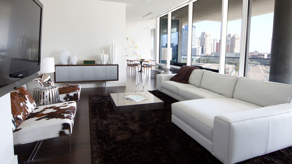 Example of a large minimalist formal and open concept dark wood floor living room design in Dallas with white walls, no fireplace and a wall-mounted tv