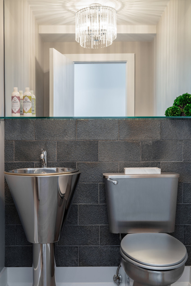 This is an example of a contemporary powder room in New York with a two-piece toilet, gray tile and a pedestal sink.