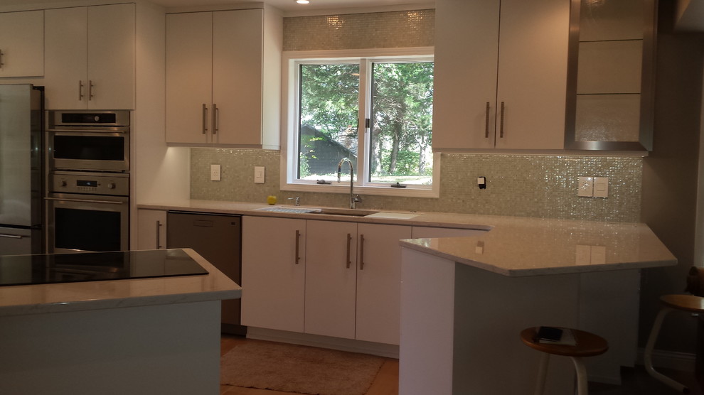 Inspiration for a small transitional galley medium tone wood floor enclosed kitchen remodel with an undermount sink, flat-panel cabinets, white cabinets, quartz countertops, white backsplash, mosaic tile backsplash and stainless steel appliances