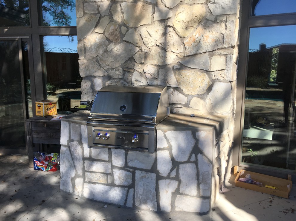 Small midcentury backyard patio in Dallas with an outdoor kitchen, natural stone pavers and no cover.