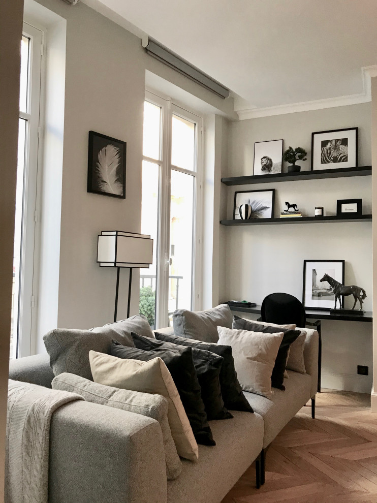 This is an example of a large contemporary open concept family room in Paris with a library, grey walls, light hardwood floors, a wall-mounted tv, brown floor and a ribbon fireplace.
