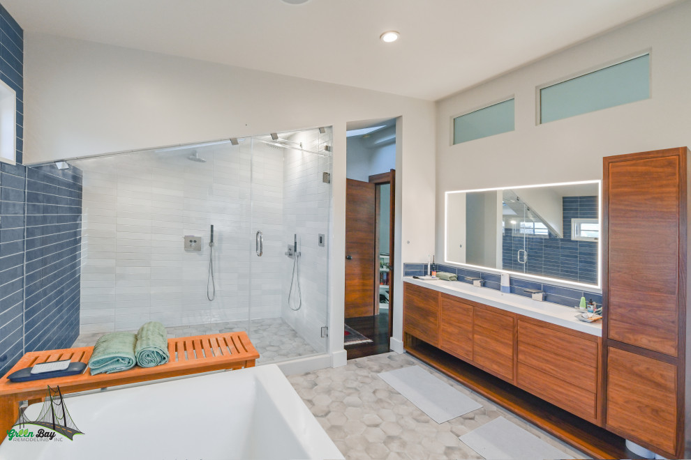 На фото: большая главная ванная комната в стиле модернизм с плоскими фасадами, отдельно стоящей ванной, душем в нише, синей плиткой, керамической плиткой, синими стенами, полом из керамической плитки, монолитной раковиной, мраморной столешницей, серым полом, душем с распашными дверями, белой столешницей, фартуком, тумбой под две раковины, светлыми деревянными фасадами и встроенной тумбой с