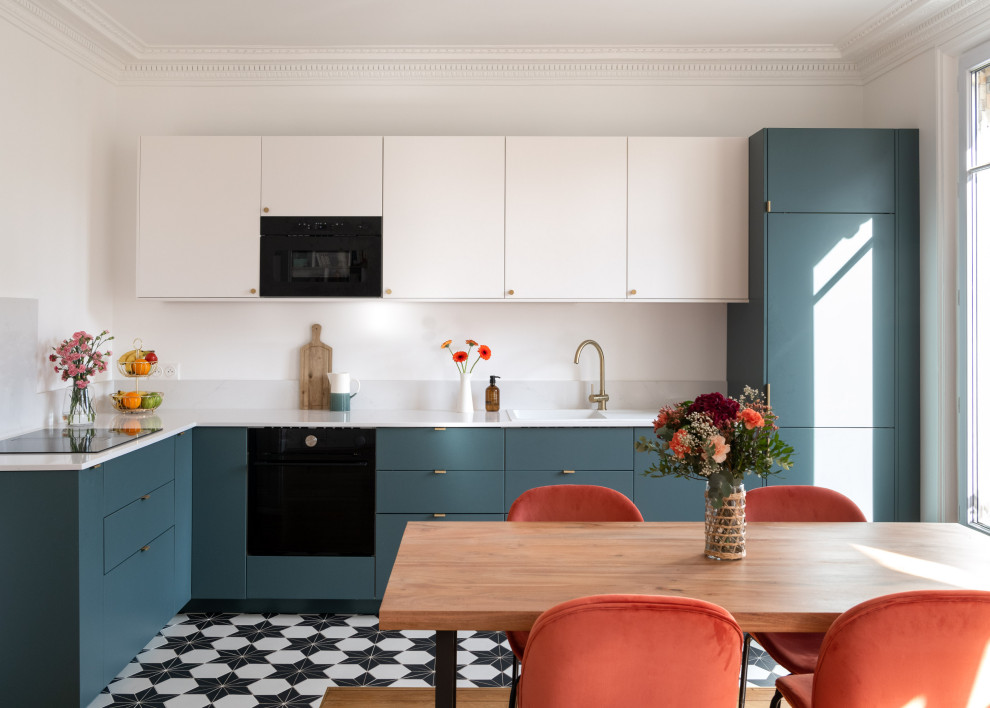 Large contemporary l-shaped open plan kitchen in Paris with a drop-in sink, flat-panel cabinets, blue cabinets, solid surface benchtops, white splashback, light hardwood floors, no island, brown floor and white benchtop.