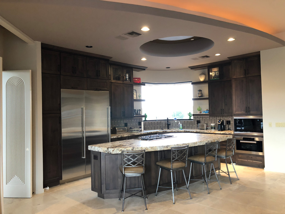 Example of a mid-sized transitional l-shaped travertine floor and white floor open concept kitchen design in Phoenix with an undermount sink, shaker cabinets, dark wood cabinets, granite countertops, subway tile backsplash, stainless steel appliances and an island