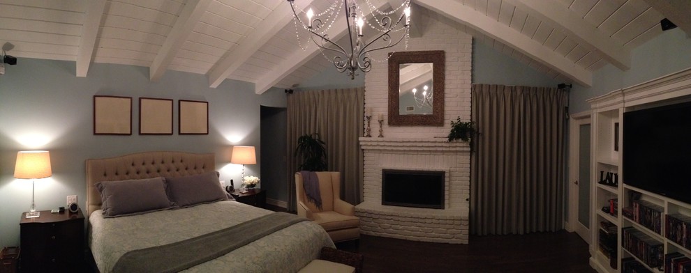 Large transitional master bedroom in San Diego with blue walls, dark hardwood floors, a standard fireplace, a brick fireplace surround and brown floor.