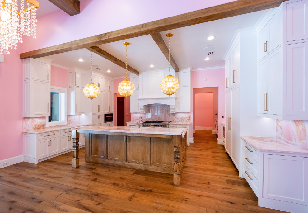Inredning av ett stort rosa rosa kök, med rosa stänkskydd, stänkskydd i marmor och en köksö
