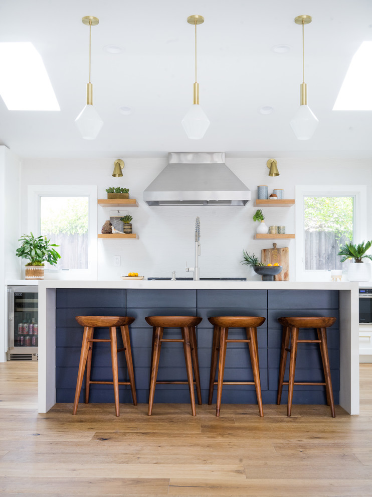 Inspiration for a mid-sized midcentury galley kitchen in Orange County with light hardwood floors, with island, white splashback and white benchtop.