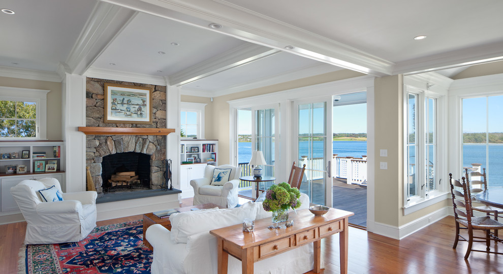 Inspiration for a mid-sized beach style open concept family room in Providence with beige walls, medium hardwood floors, a standard fireplace, a stone fireplace surround and brown floor.