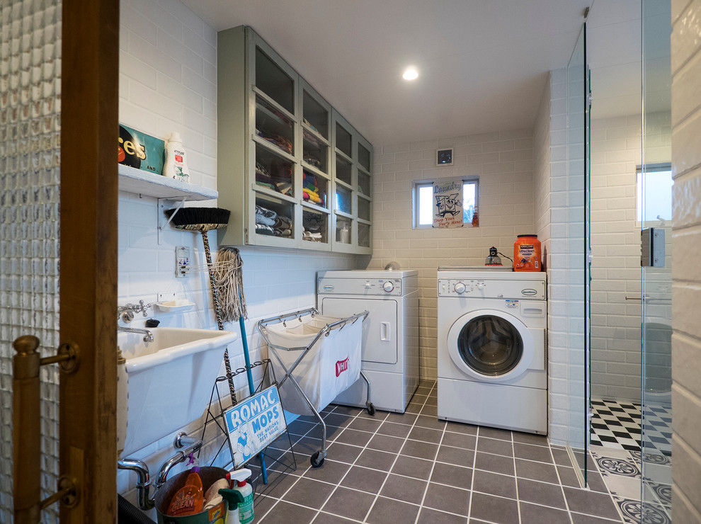 Inspiration for a mediterranean single-wall dedicated laundry room in Tokyo with a single-bowl sink, glass-front cabinets, white walls, ceramic floors, a side-by-side washer and dryer and grey cabinets.