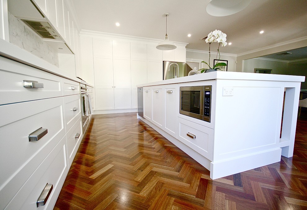 Inspiration for a large transitional l-shaped open plan kitchen in Sydney with an undermount sink, shaker cabinets, white cabinets, quartz benchtops, white splashback, stone tile splashback, stainless steel appliances, dark hardwood floors and with island.