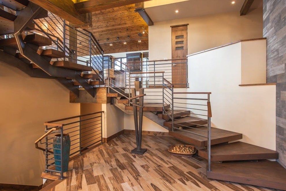 This is an example of a mid-sized country wood curved staircase in Albuquerque with open risers and cable railing.