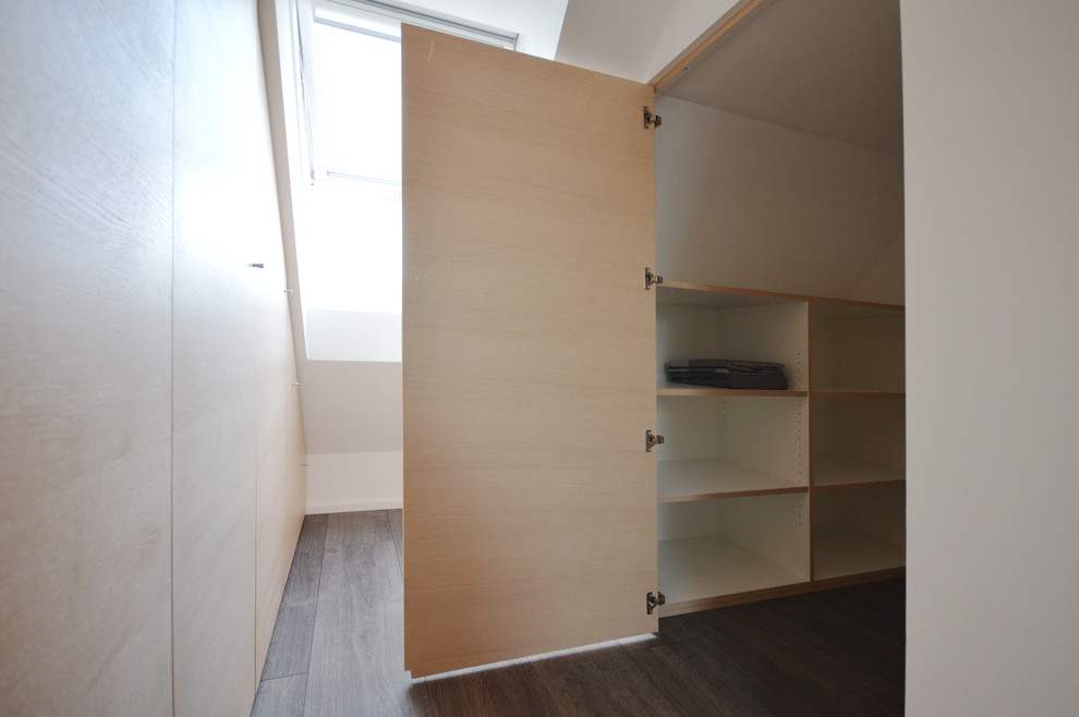 Photo of a mid-sized contemporary women's walk-in wardrobe in Munich with flat-panel cabinets, light wood cabinets, dark hardwood floors and grey floor.