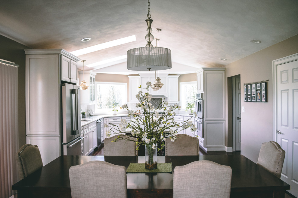 Transitional u-shaped brown floor and dark wood floor kitchen/dining room combo photo in New York with an undermount sink, recessed-panel cabinets, white cabinets, granite countertops, multicolored backsplash, glass tile backsplash, stainless steel appliances, an island and multicolored countertops