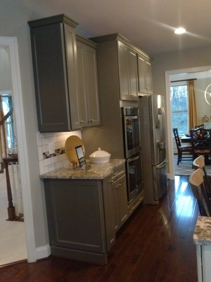 Eat-in kitchen - mid-sized transitional l-shaped medium tone wood floor and red floor eat-in kitchen idea with an undermount sink, raised-panel cabinets, gray cabinets, granite countertops, multicolored backsplash, subway tile backsplash, stainless steel appliances, an island and multicolored countertops