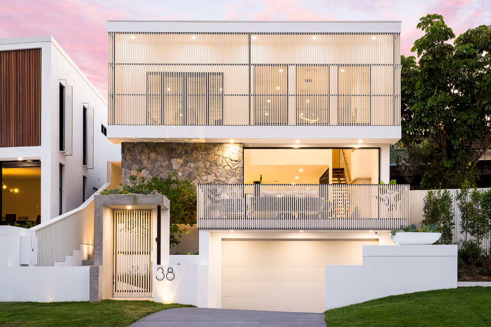 Photo of a large contemporary three-storey white house exterior in Brisbane with a flat roof and a metal roof.