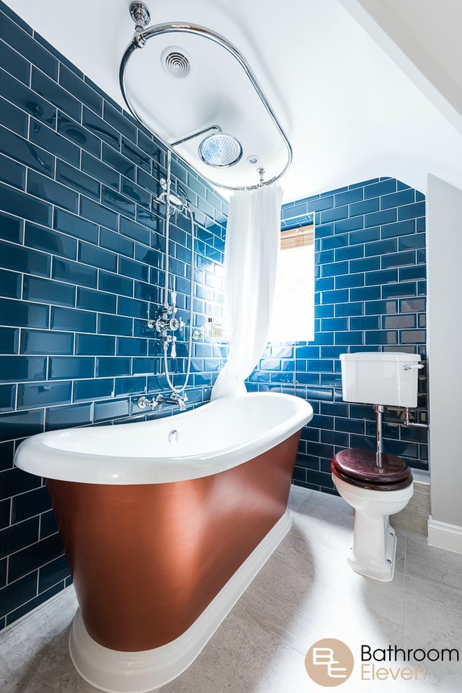 Inspiration for an eclectic kids bathroom in Hampshire with furniture-like cabinets, a freestanding tub, a shower/bathtub combo, a two-piece toilet, blue tile, ceramic tile, white walls, ceramic floors, a pedestal sink, solid surface benchtops, beige floor and a shower curtain.