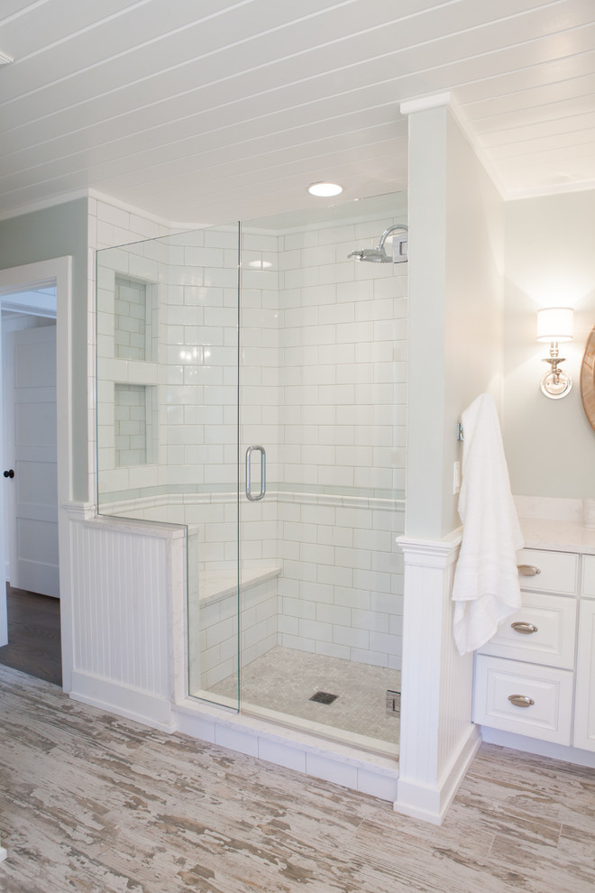 This is an example of a mid-sized country master bathroom in Chicago with an undermount sink, raised-panel cabinets, white cabinets, a corner shower, subway tile, green walls, porcelain floors and white tile.