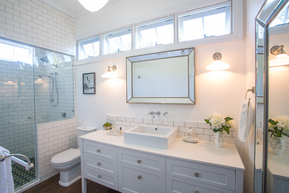 This is an example of a large traditional master bathroom in Brisbane with furniture-like cabinets, white cabinets, a curbless shower, a one-piece toilet, white tile, subway tile, white walls, concrete floors, a vessel sink and engineered quartz benchtops.