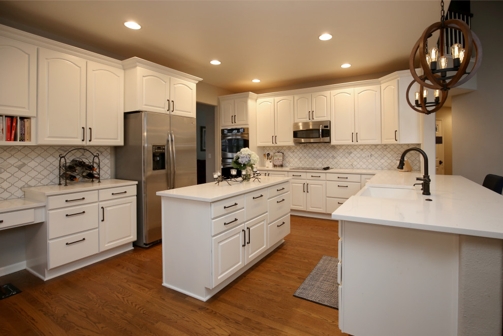 Mid-sized beach style u-shaped eat-in kitchen in Denver with recessed-panel cabinets, white cabinets, quartz benchtops, multi-coloured splashback, porcelain splashback, stainless steel appliances, dark hardwood floors, with island, brown floor, white benchtop and a farmhouse sink.
