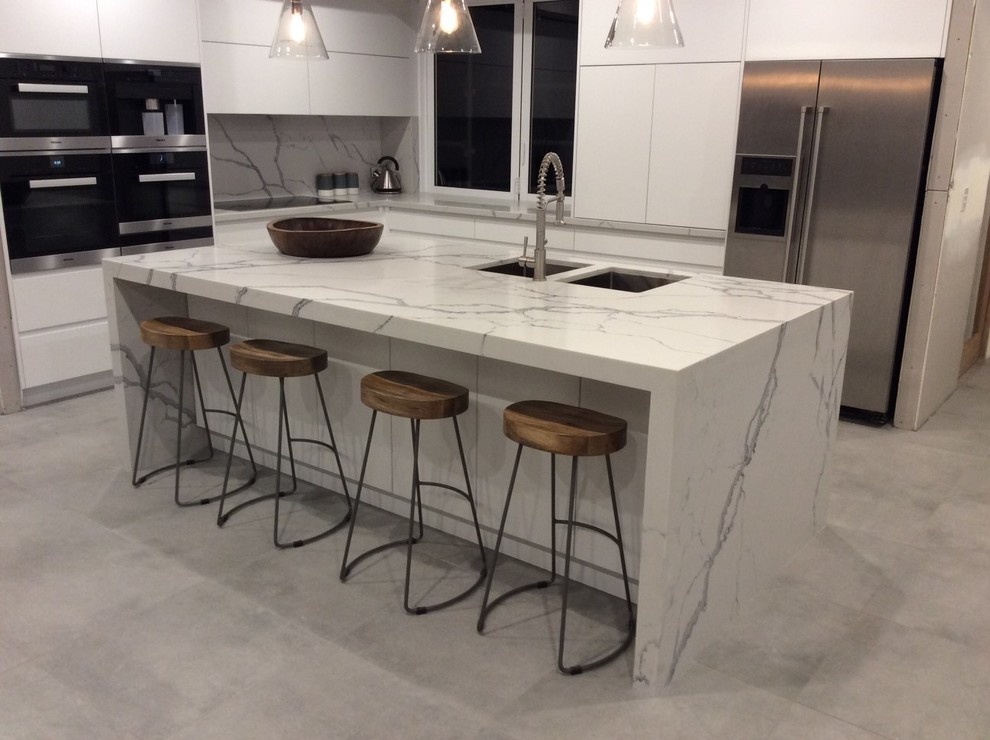 Large modern l-shaped eat-in kitchen in Sydney with an undermount sink, quartz benchtops and with island.