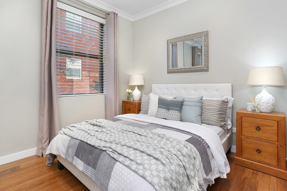 This is an example of a transitional master bedroom in Sydney with grey walls and medium hardwood floors.