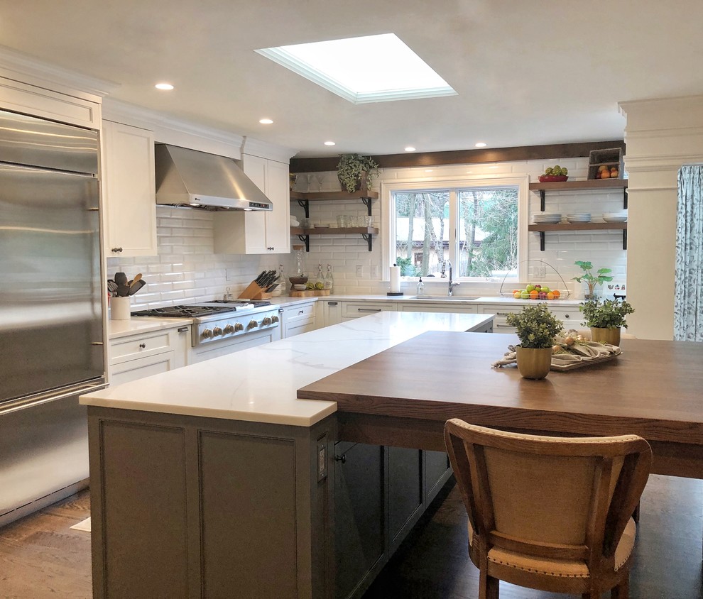 Huge transitional dark wood floor and brown floor eat-in kitchen photo with an undermount sink, shaker cabinets, white cabinets, quartz countertops, white backsplash, porcelain backsplash, stainless steel appliances, an island and white countertops
