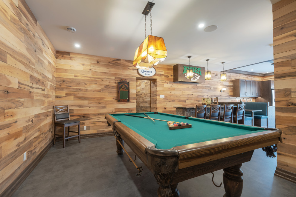Large mountain style walk-out vinyl floor, gray floor, exposed beam and wood wall basement photo with a bar, multicolored walls, a standard fireplace and a stone fireplace
