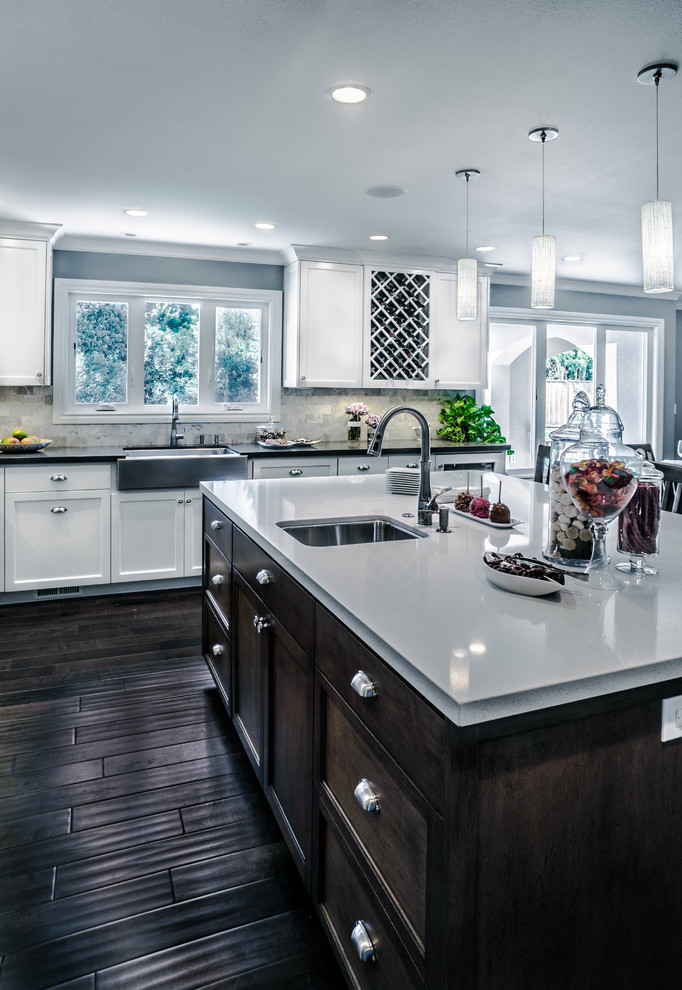 This is an example of a large transitional u-shaped eat-in kitchen in San Francisco with a farmhouse sink, recessed-panel cabinets, white cabinets, quartz benchtops, beige splashback, stone tile splashback, stainless steel appliances, dark hardwood floors, with island and black floor.