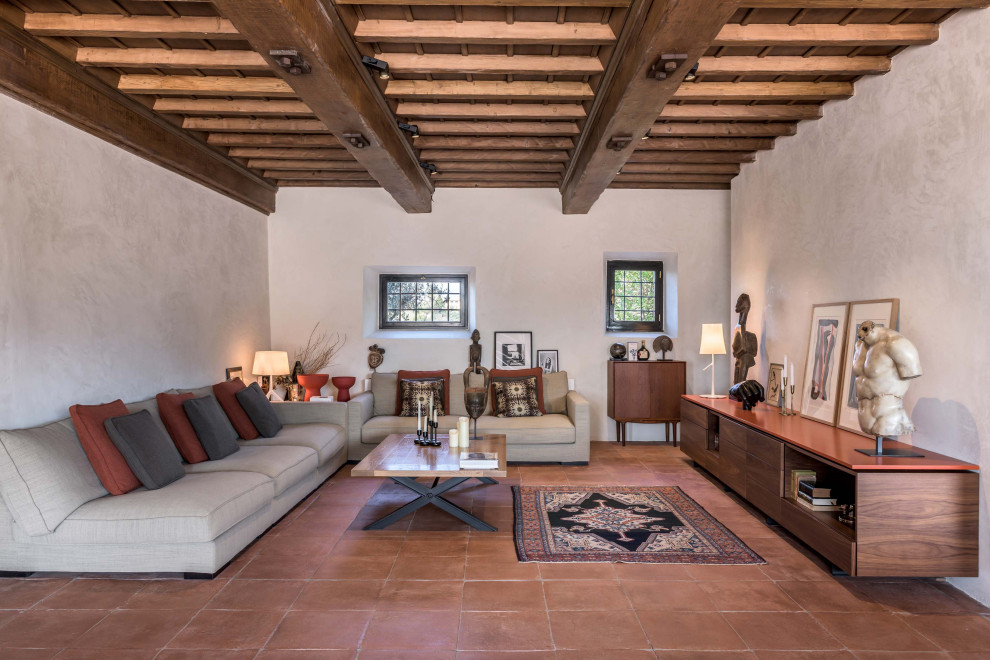 This is an example of a mediterranean open concept living room in Florence with white walls, terra-cotta floors, no fireplace, no tv, orange floor and exposed beam.