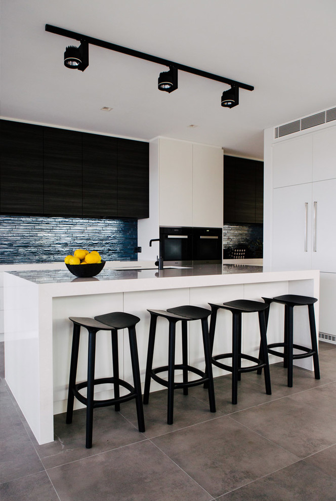 Contemporary single-wall open plan kitchen in Sydney with an undermount sink, flat-panel cabinets, white cabinets, blue splashback, matchstick tile splashback, stainless steel appliances, concrete floors and with island.