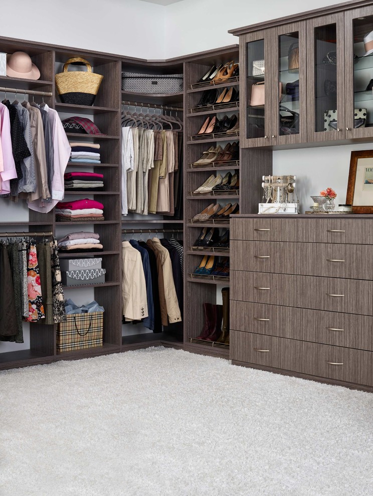 This is an example of a large traditional women's walk-in wardrobe in Seattle with flat-panel cabinets, brown cabinets and carpet.