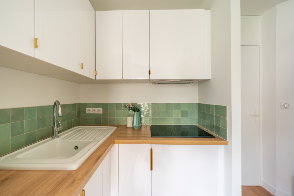 Inspiration for a small contemporary l-shaped open plan kitchen in Nantes with an undermount sink, beaded inset cabinets, white cabinets, wood benchtops, green splashback, porcelain splashback, medium hardwood floors, no island, brown floor and beige benchtop.