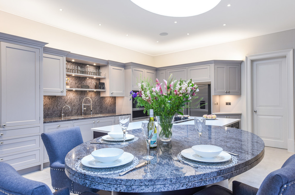 Photo of an expansive traditional open plan kitchen in London with a double-bowl sink, shaker cabinets, grey cabinets, granite benchtops, grey splashback, stone slab splashback, panelled appliances, with island and blue benchtop.