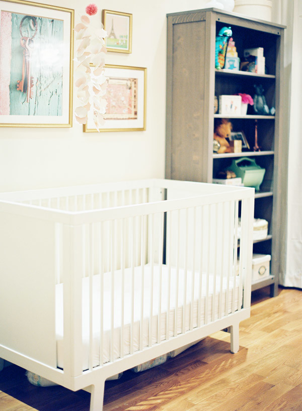 This is an example of a small traditional nursery for girls in New York with white walls and medium hardwood floors.