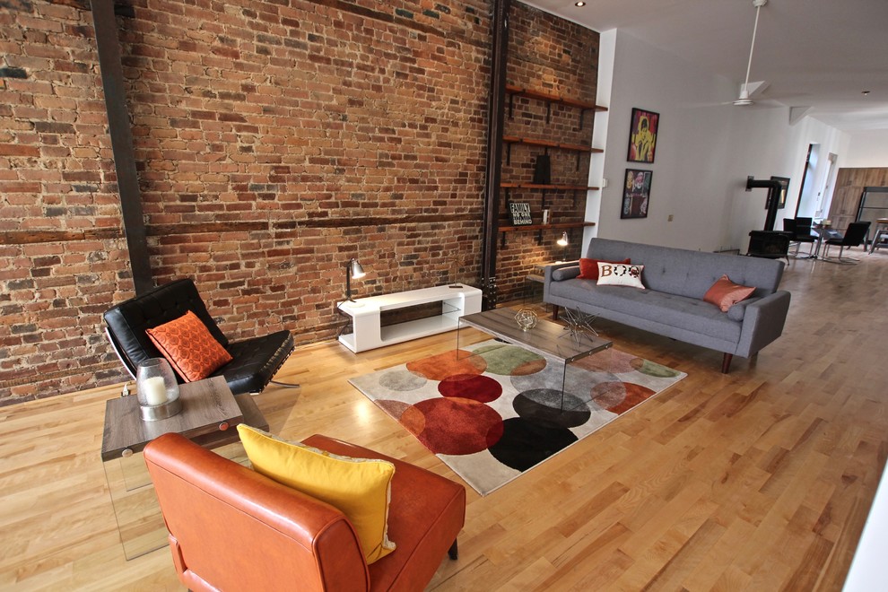 This is an example of a large industrial open concept living room in Montreal with red walls, light hardwood floors and no fireplace.