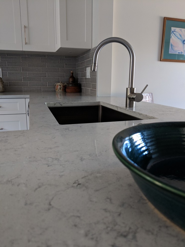 Inspiration for a small transitional u-shaped vinyl floor and beige floor eat-in kitchen remodel in Vancouver with a single-bowl sink, shaker cabinets, white cabinets, quartz countertops, gray backsplash, ceramic backsplash, stainless steel appliances, no island and gray countertops