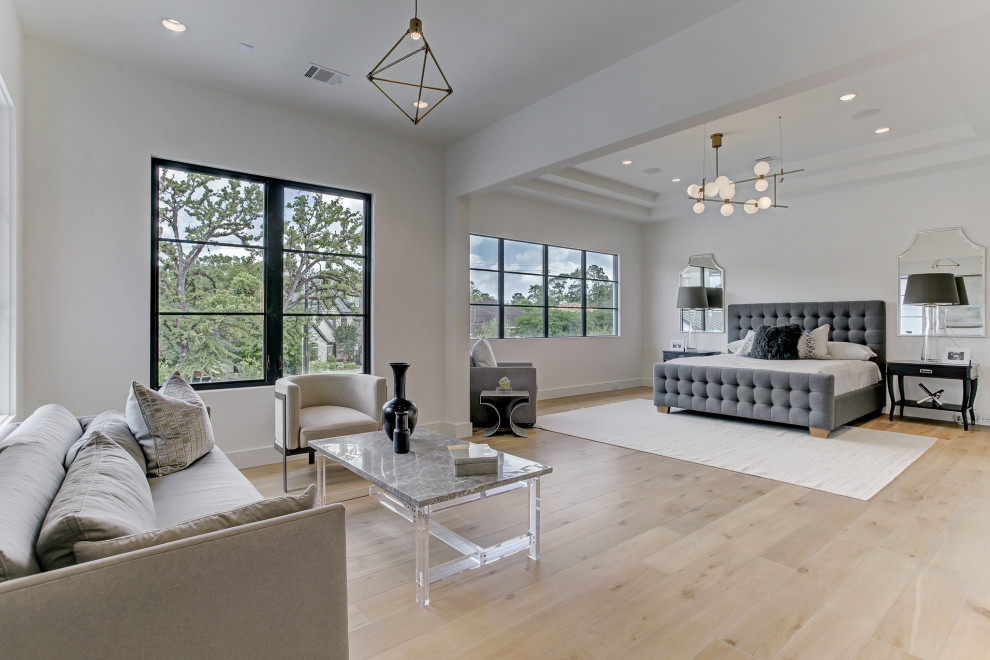 Design ideas for a large mediterranean master bedroom in Houston with white walls, light hardwood floors and beige floor.