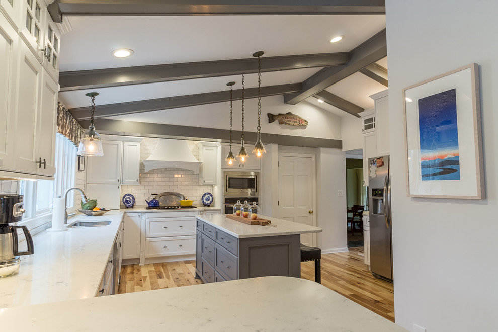 Large transitional u-shaped medium tone wood floor and brown floor enclosed kitchen photo with an undermount sink, shaker cabinets, white cabinets, quartzite countertops, white backsplash, subway tile backsplash, stainless steel appliances and an island