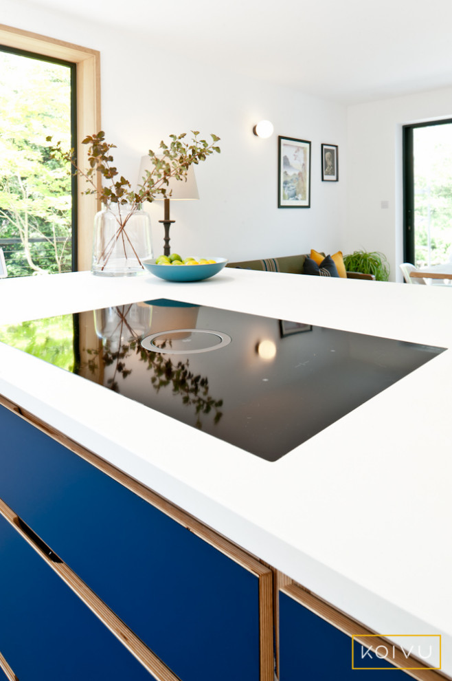 На фото: большая прямая кухня в современном стиле с обеденным столом, плоскими фасадами, синими фасадами, столешницей из кварцита, островом и белой столешницей с