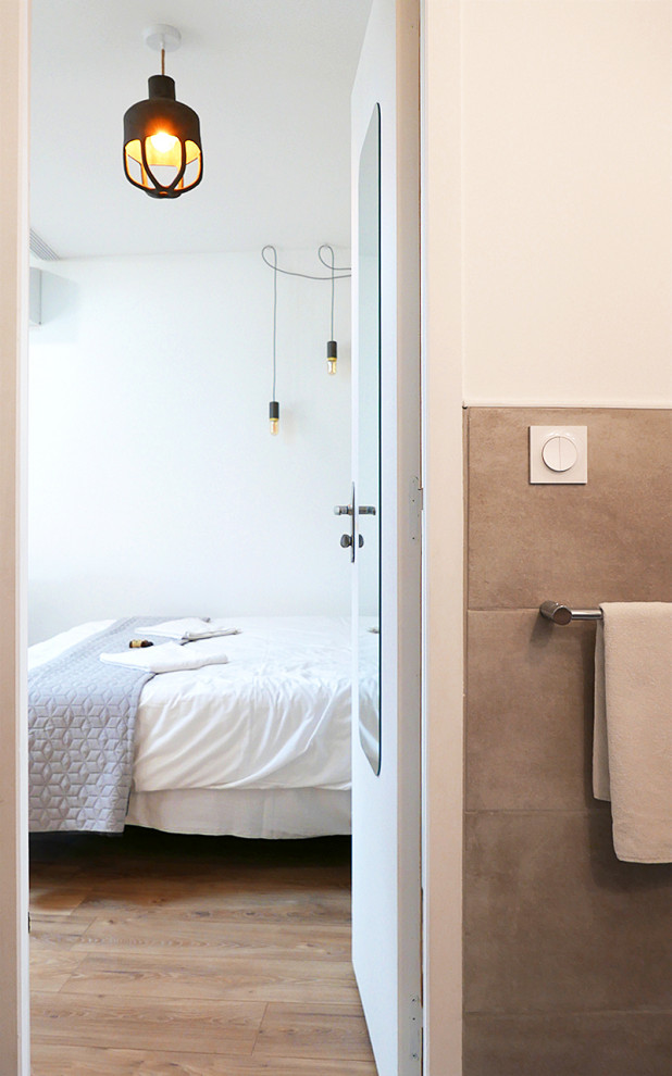 Foto di una piccola stanza da bagno con doccia mediterranea con ante in legno chiaro, WC sospeso, piastrelle grigie, piastrelle di marmo, pavimento in laminato, porta doccia a battente, toilette, un lavabo e mobile bagno sospeso