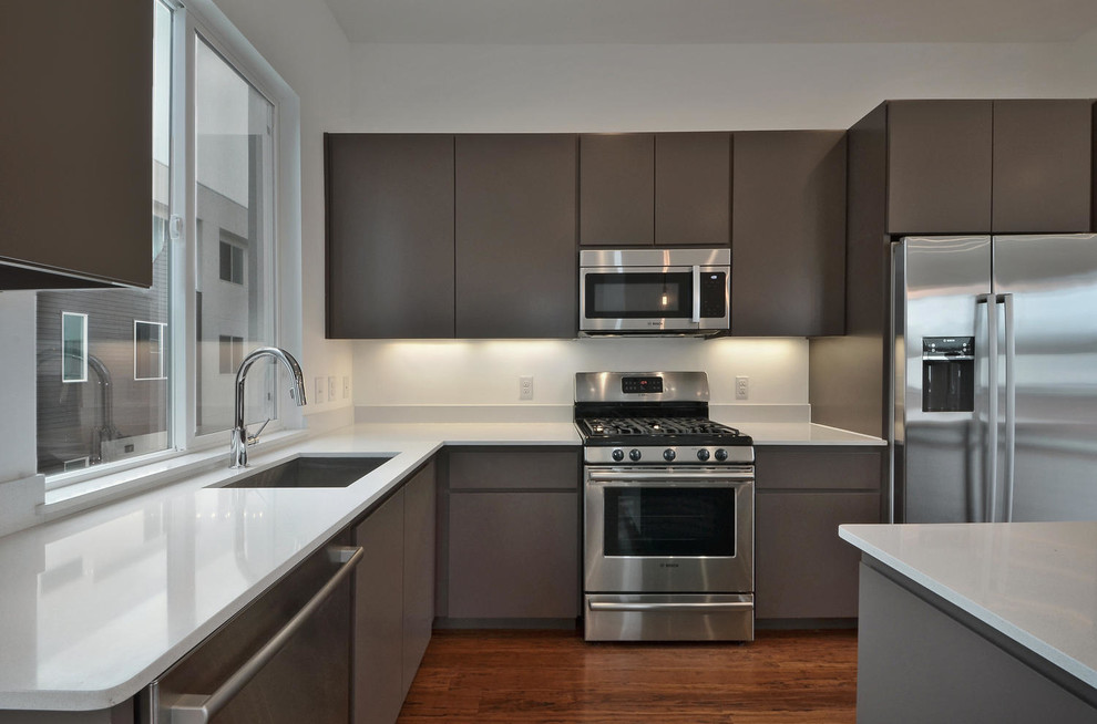 Mid-sized modern l-shaped eat-in kitchen in Austin with an undermount sink, flat-panel cabinets, brown cabinets, quartz benchtops, stainless steel appliances, bamboo floors and with island.