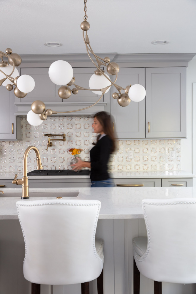Example of a transitional dark wood floor and brown floor kitchen design with a drop-in sink, shaker cabinets, gray cabinets, quartzite countertops, white backsplash, mosaic tile backsplash, stainless steel appliances, an island and white countertops