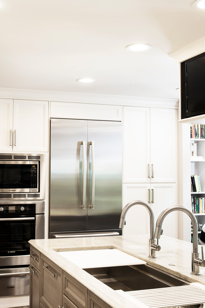 Kitchen - large transitional single-wall medium tone wood floor and brown floor kitchen idea in Denver with an undermount sink, recessed-panel cabinets, white cabinets, white backsplash, stone slab backsplash, stainless steel appliances and an island