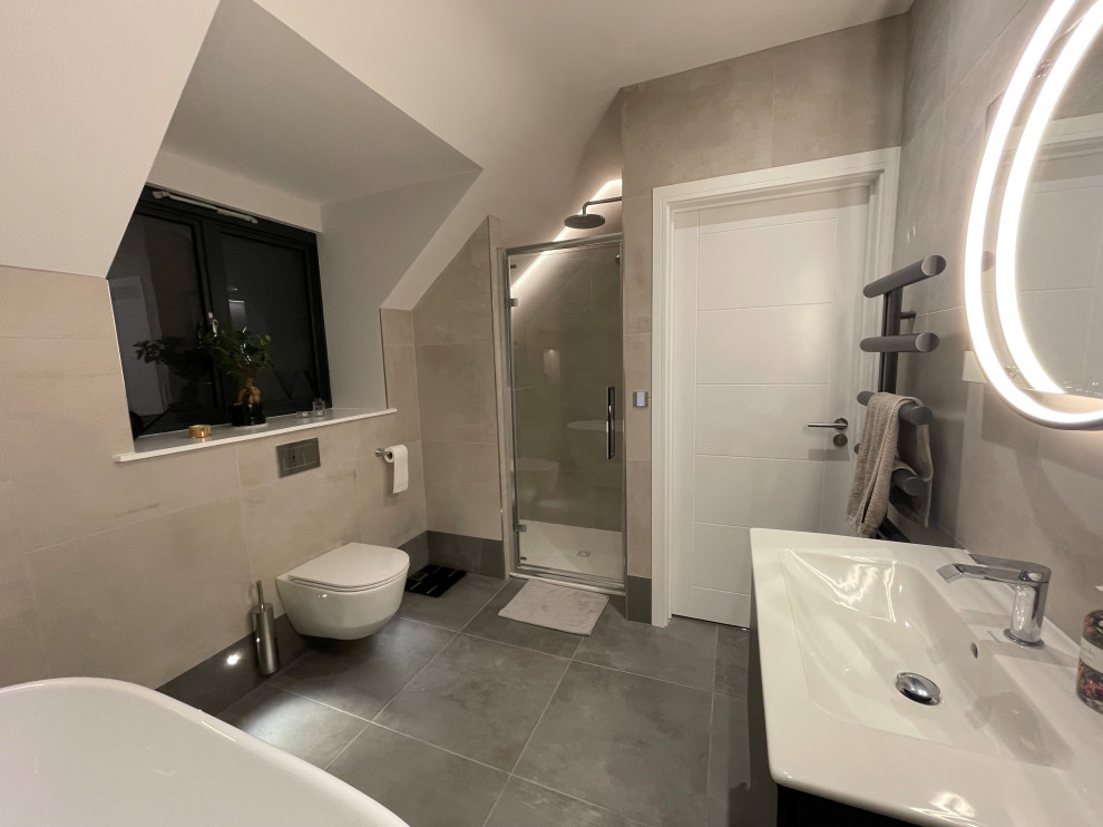 Photo of a small contemporary family bathroom in Buckinghamshire with flat-panel cabinets, grey cabinets, a freestanding bath, a walk-in shower, a wall mounted toilet, grey tiles, porcelain tiles, white walls, ceramic flooring, a built-in sink, grey floors, an open shower, a single sink and a floating vanity unit.
